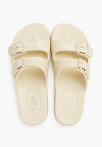 Sandalias color crema con dos hebillas ajustables, hechas de material texturizado, que presentan una plantilla contorneada y una superficie suave.