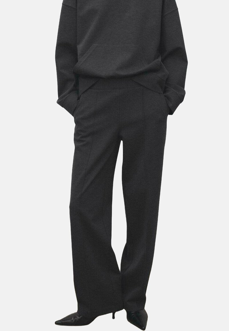 Pantaloni a gamba larga grigio scuro in tessuto strutturato con pieghe frontali e tasche laterali, abbinati a una maglia abbinata dal taglio ampio.