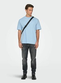 Light blue cotton t-shirt; round neckline, short sleeves. Paired with dark grey denim jeans and black ankle boots. Minor shoulder bag detail.