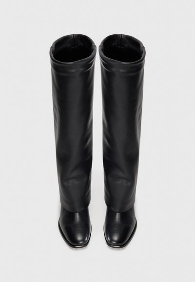 Black leather knee-high boots with a soft texture, pointed toes, and a wide, folded cuff at the top. Square-shaped heel design.