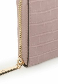 Portafoglio in pelle sintetica effetto coccodrillo rosa chiaro con zip e dettaglio del tirazip dorati. Esterno texturizzato con una finitura liscia.