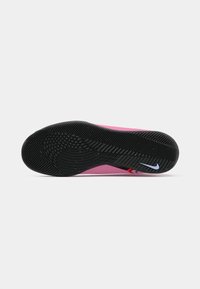 Nike cipő fekete gumitalppal, amely textúrázott tapadási mintákkal rendelkezik, rózsaszín középtalppal és egy kis kék logó akcentussal.