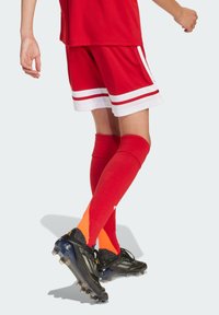 Maillot de sport rouge et shorts avec des rayures blanches, accompagné de chaussettes rouges mi-mollet avec des accents orange, et des chaussures de football noires.