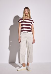 Triko s maroon a bílými pruhy, krátké rukávy, kombinované s širokými světle béžovými kalhotami a bílými teniskami. Jednoduchý, casualní design.