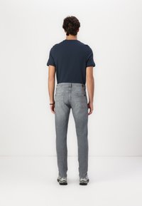 Grå denimjeans med slim fit, fem lommer og subtile sømdetaljer, kombinert med en mørkeblå t-skjorte med kort erme.