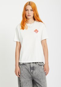 White cotton t-shirt featuring a colorful mushroom and diamond graphic on the chest. Relaxed fit with short sleeves.