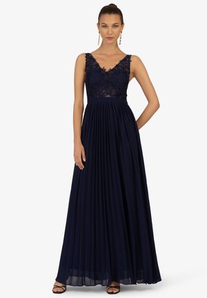 Marineblaue Abendkleid mit einem Spitzenoberteil, V-Ausschnitt und plissiertem Rock. Besitzt breite Träger und eine taillierte Taille. Weiche, fließende Stoff.