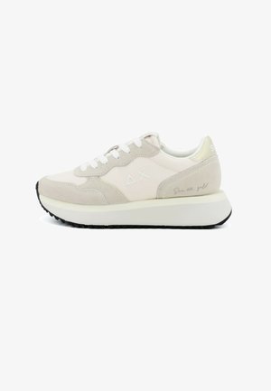 Zapatilla beige y blanca con cordones blancos, suela elevada, detalles en ante y logo minimalista en el lateral y el talón.
