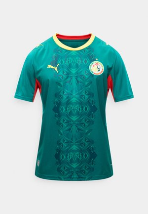 Roheline jalgpallivorm kollase äärisega, punaste külgpaneelide, geomeetrilise keskmise mustri, Puma logoga ja Senegal jalgpalliföderatsiooni vapi ning tähega üleval.
