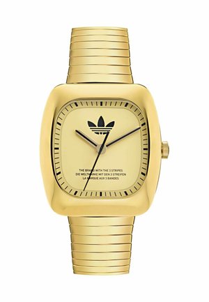 Montre rectangulaire dorée avec un bracelet en métal rainuré, cadran minimaliste avec des index horaires noirs et un logo, et deux aiguilles fines.