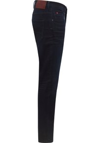 Ciemnoniebieskie dżinsy o wąskim kroju, z tylnymi kieszeniami i skórzaną naszywką na pasku. Gładka tekstura z minimalnymi detalami.