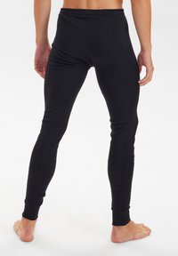Black fitted leggings made of a soft, stretchy material, featuring a seamless waistband and tapered cuffs. No visible patterns or accents.