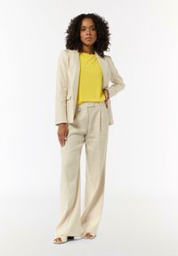 Beige blazer and wide-leg trousers paired with a bright yellow top. Smooth fabric, tailored fit, and minimalistic design.