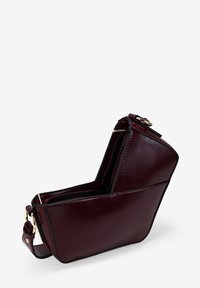 Bolso de cuero burdeos con forma geométrica, que cuenta con un cierre con cremallera, acentos en hardware dorado y costuras negras contrastantes.