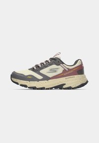 Chaussure de trail beige, grise et marron avec une semelle robuste, un design à lacets et un marquage sur le côté et le talon.