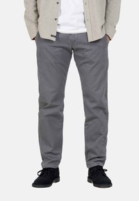 Gray trousers, cotton blend, straight fit. Features front pockets and a button closure. Paired with black shoes and a light-colored shirt.