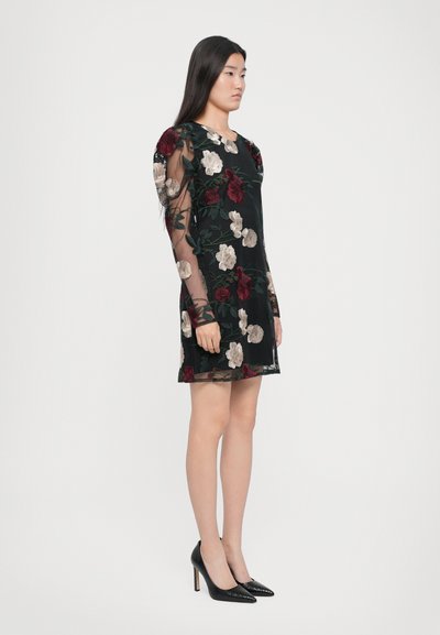 Zwart bloemenjurk met doorschijnende lange mouwen, voorzien van geborduurde rozen in rood en crèmekleur. Draag met zwarte hoge hakken.
