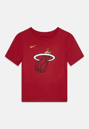 Raudona medvilninė marškinė su juodu ir geltonu Miami Heat logotipu, kuriame pavaizduotas krepšinio kamuolys ir liepsna. Trumpomis rankovėmis ir apvaliu kaklu.