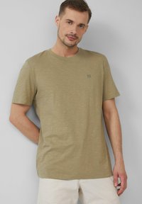 Oliwkowa koszulka z krótkim rękawem wykonana z miękkiego, strukturalnego materiału. Posiada okrągły dekolt oraz małe logo na piersi. Luźny krój.