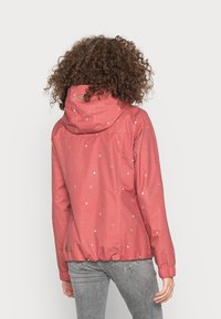 Red, water-resistant jacket with a hood, featuring a subtle dot pattern and elastic cuffs. Relaxed fit with a cinched hem.