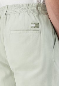 Svijetlozelene korduroy hlače s elastičnom strukom, s stražnjim džepom i oznakom marke Tommy Jeans sa strane.
