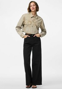 Veste en jean cropped de couleur beige clair avec deux poches avant et des boutons ; associée à un pantalon large taille haute noir.