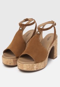 Sandali platform in suede marrone con tacco in sughero, punta aperta, cinturino alla caviglia e dettagli in metallo per una vestibilità sicura.