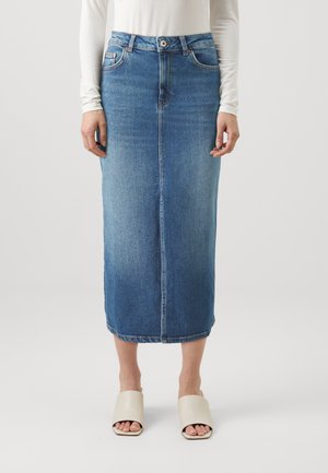 Jeanskjørt med rett snitt, middels lengde, i lys blå vask. Har frontknapping, beltehemper og lett falming, brukt med beige sandaler.