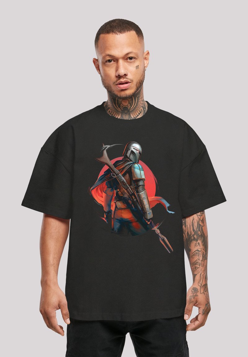 Svart oversized t-skjorte med en illustrasjon av en pansret karakter som holder et våpen, bakgrunnet av et rødt sirkulært design.