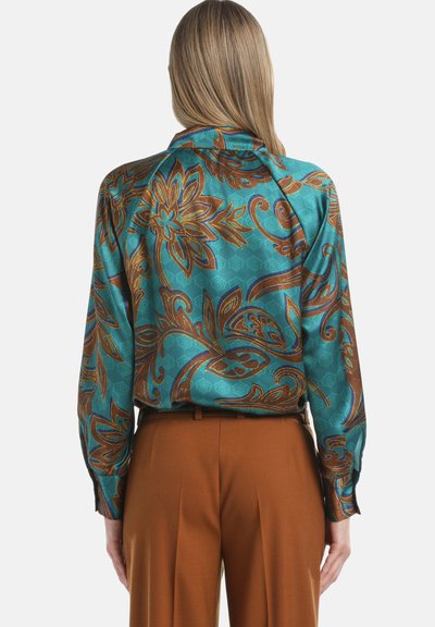 Turquoise zijden blouse met bruine bloemen- en spiraalpatronen, lange mouwen en een ontspannen pasvorm. Bevat een kraag en knoopmanchetten.