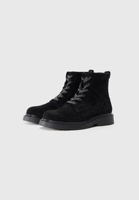 Black suede ankle boots with gray laces, rounded toe, textured surface, and a thick black rubber sole. No notable embellishments.