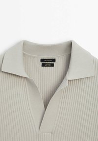 Haut en maille côtelée gris clair avec un col rabattu et un design en V. Présente une étiquette noire avec "Massimo Dutti" et des instructions d'entretien.