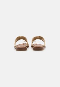 Tan väldämpande sandaler med korsande remdesign, läderöverdel och en brun strukturerad sula. Öppen bakdel med minimal hårdvarudetalj.
