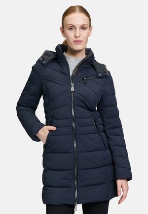 Marineblauwe gewatteerde pufferjas met rits aan de voorkant, dubbele zijzakken en schouderaccenten. Voorzien van een capuchon en een zachte, textuurcollar.