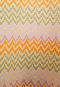 Tessuto con un motivo a zigzag in toni di arancione, grigio e viola su uno sfondo beige. Il design è audace e ripetitivo.