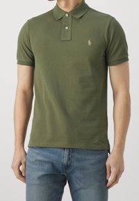 Polo shirt verde a maniche corte realizzato in cotone liscio. Presenta un colletto a punta e un piccolo logo ricamato sul petto. Design aderente.