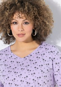 Lavendel V-hals T-shirt med et gentaget sort palme-træ mønster, lavet af blødt materiale med en afslappet pasform og korte ærmer.