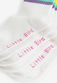 Biele ponožky s rebrovanou textúrou majú na bokoch ružový nápis "Little Bird", doplnené farebným pruhovaným vzorom na vrchu.