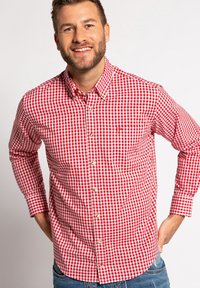 Rot-weiß kariertes Button-up-Hemd mit langen Ärmeln, Kragen, Fronttasche und goldfarbenen Knöpfen, kombiniert mit blauen Jeans.