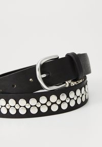 Ceinture en cuir noir avec une texture lisse, dotée de grands clous en argent sur toute sa longueur et d'une boucle en métal, conçue pour la fermeture.