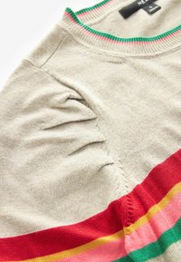 Beige stickad topp med ribbat runt halsringning som har gröna och rosa ränder. Röda, gula och rosa horisontella ränder i botten.