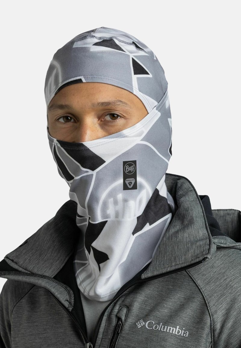 Buff balaclava in a gray and white geometric pattern, made of soft, stretchy fabric. Worn over the face, paired with a gray jacket.