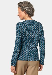Langärmliges Oberteil mit einem blauen und grauen geometrischen Muster, aus weichem Stoff mit taillierter Passform und rundem Ausschnitt.