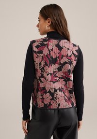 Prsluk s cvjetnim uzorkom na crnoj podlozi, s ružičastim i kremasto-bijelim cvjetnim dizajnom; izrađen od teksturirane tkanine s prilagođenim siluetom.