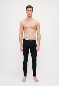 Schwarze Leggings aus einem dehnbaren Stoff mit einer figurbetonten Passform, versehen mit einem weißen Elastikbund mit dem Branding "JACK & JONES".
