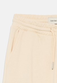 Calvin Klein beige joggebukser med elastisk linning, snøring, sidelommer og myk teksturert stoff.