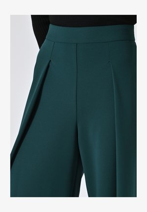 Weite, türkisfarbene Hosen mit gefälteltem Detail an der Taille. Hergestellt aus einem glatten Stoff mit matter Oberfläche.