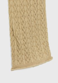 Dziana szalik w odcieniu beżu, z wzorem w warkocze i ażurowymi ściegami. Teksturowane krawędzie z ściągaczem. Gładki wygląd materiału.