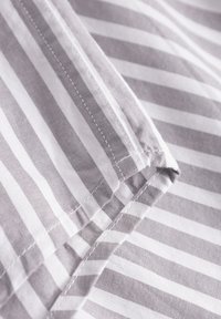 Gray and white striped fabric showing smooth texture and neat stitching along the edges. The stripes are of equal width throughout.
