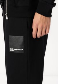 Sorte jogger med et læderlignende patch med "KARL LAGERFELD JEANS" logo. Fremstillet af fleece-materiale, der viser en tætsiddende pasform og lommepynt.